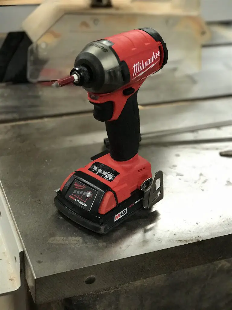 Red cordless impact driver on workbench.