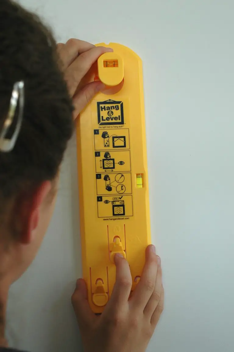 Person using yellow Hang & Level tool on wall.