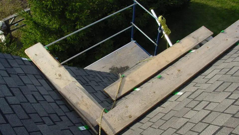 Roof shingles with wooden planks and scaffolding setup.
