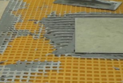 Tile installation on orange grid mat.