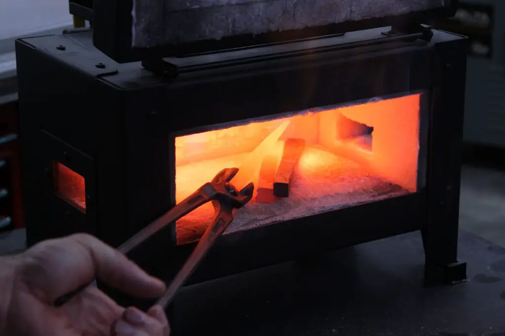 Heating metal in forge with tongs