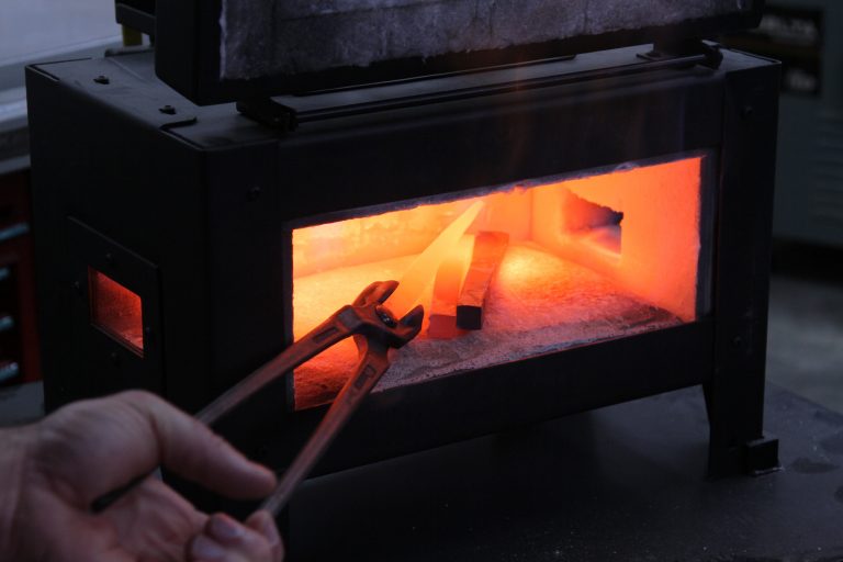 Heating metal in forge with tongs