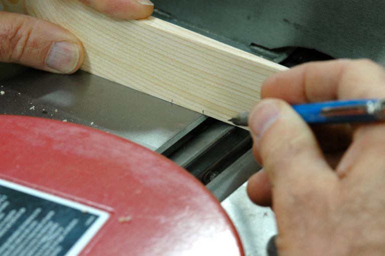 Person marking wood for cutting with pencil