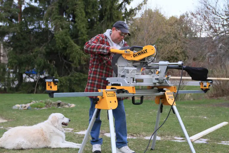 Man using miter saw in backyard with dog