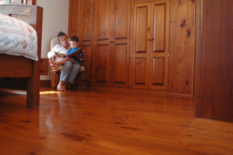 Person reading book to child in wooden room.