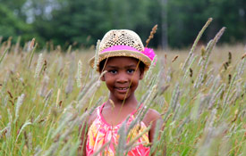 little girl playing in a field in tall grass