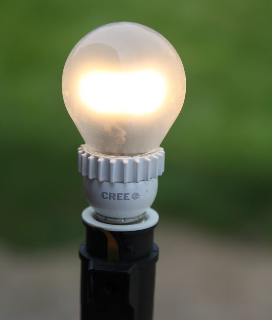 Illuminated Cree LED light bulb on stand.