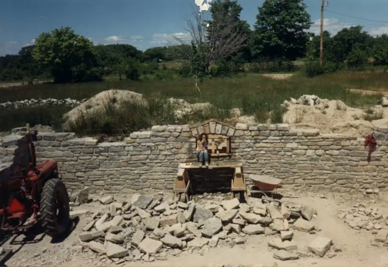 Person sitting on stone wall under construction