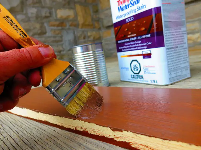 Applying waterproof stain to wood with brush