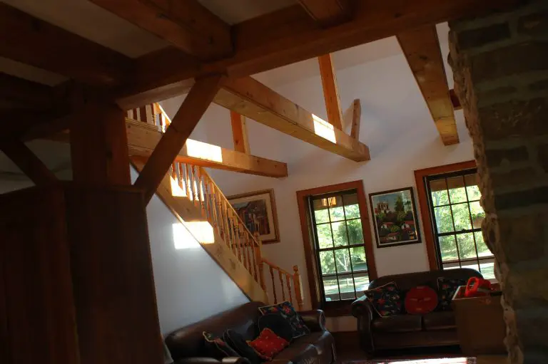 Sunlit living room with wooden beams and staircase.