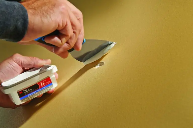 Applying wall patch with putty knife.