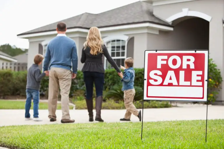 Family viewing house with for sale sign.