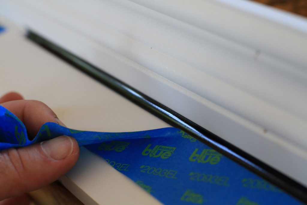 Applying blue painter's tape to window frame