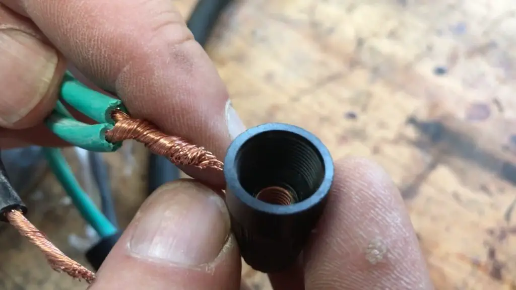 Connecting copper wire to black connector close-up.