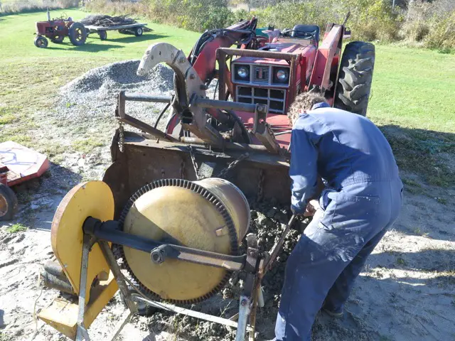 Person operating a tractor with mixer attachment.