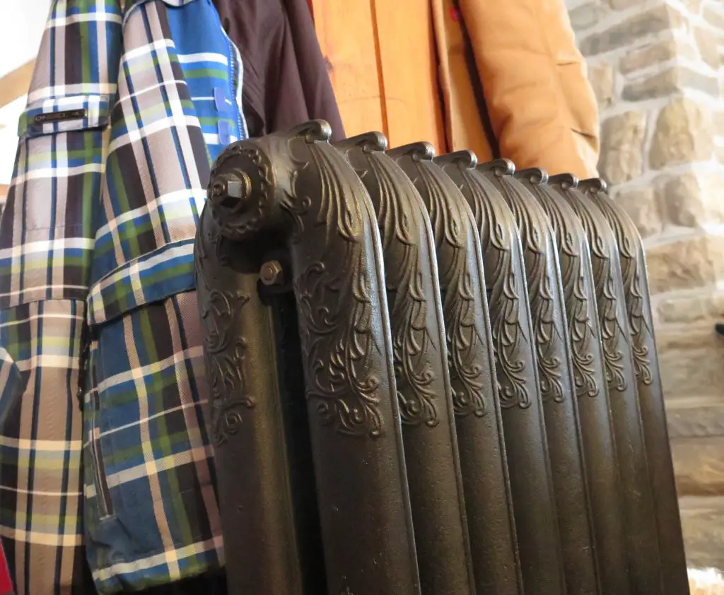 Classic cast iron radiator with coats hanging nearby.