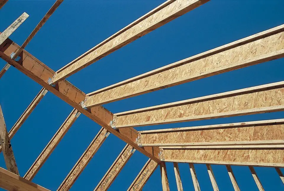Wooden roof framework under clear blue sky.