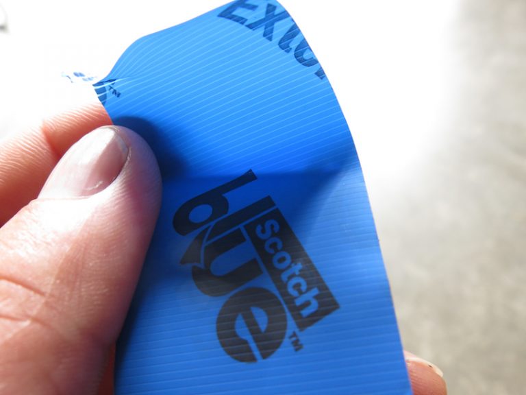 Hand holding blue Scotch tape strip