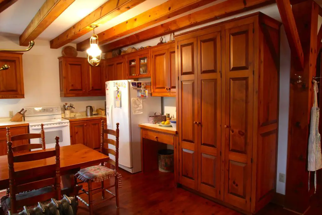 Rustic wooden kitchen with dining area and fridge.