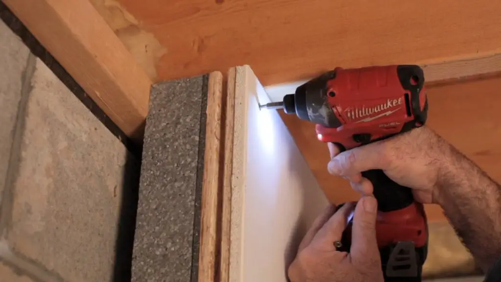 Person using a drill on a white board.