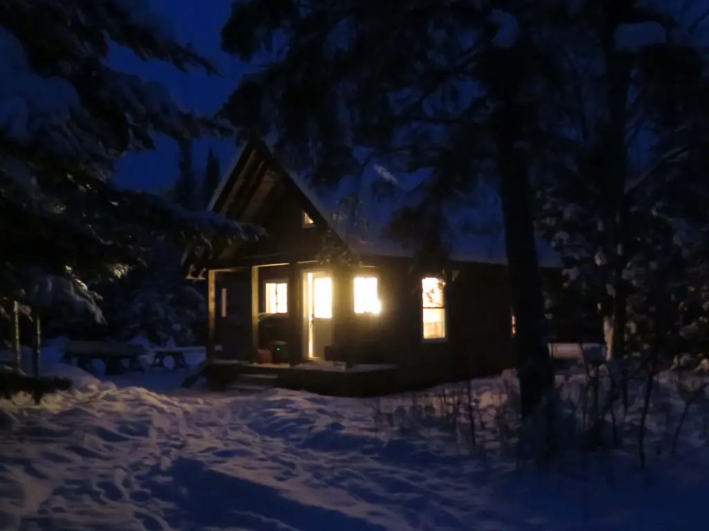 Cozy cabin illuminated in snowy winter night