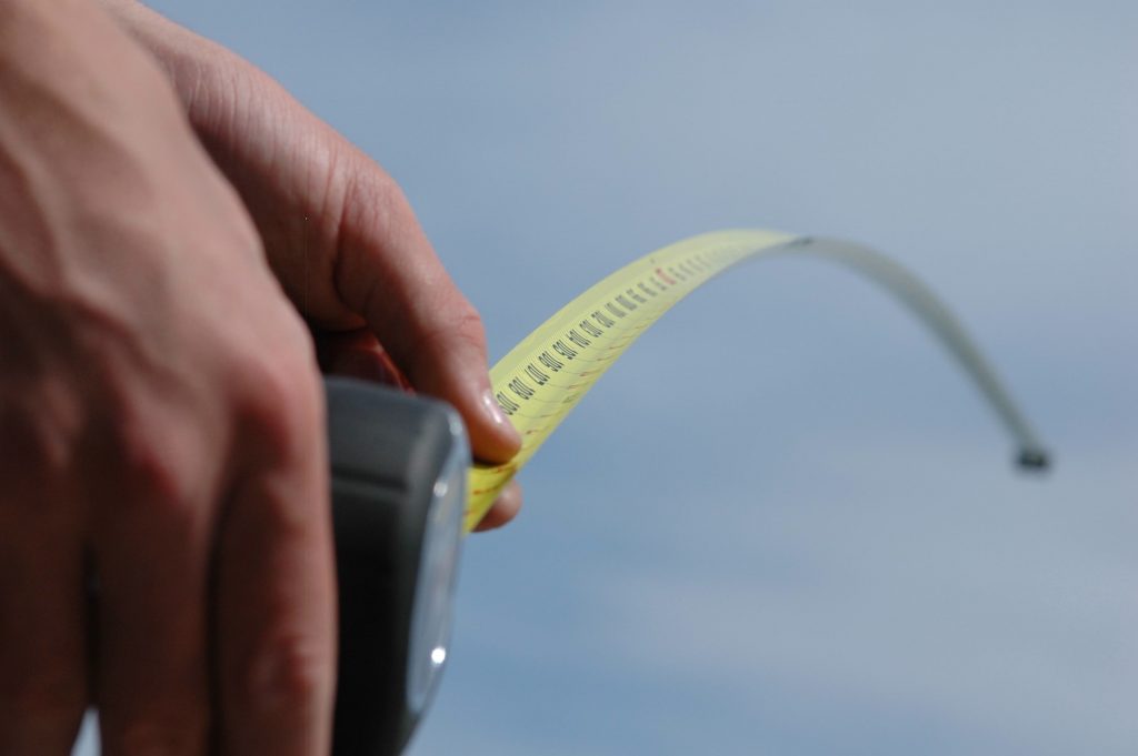 Hand holding extended measuring tape.