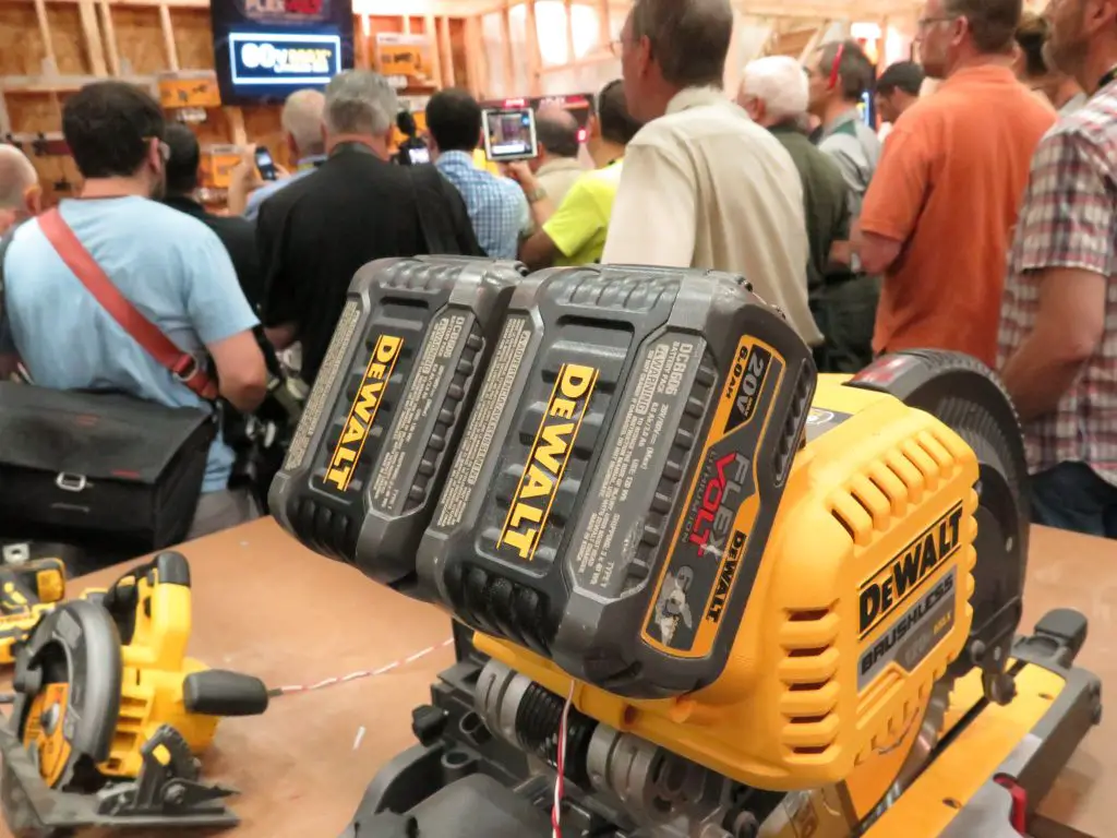 Crowd watching power tools demonstration in workshop.