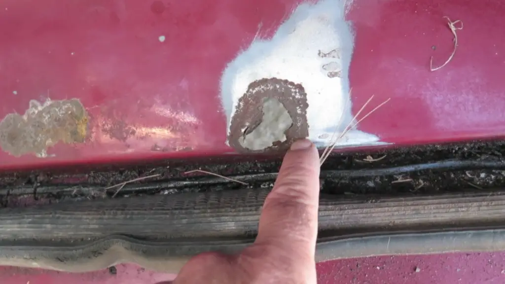 Finger pointing at rust on car door edge.