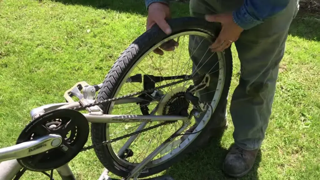 Person fixing bicycle tire on grass