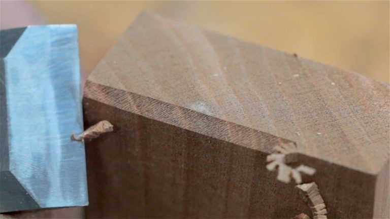 Chisel cutting corner of wood block close-up