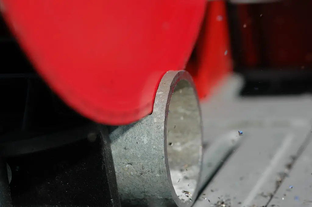 Saw cutting metal pipe close-up
