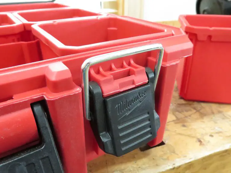 Red plastic toolbox with black latch on bench.
