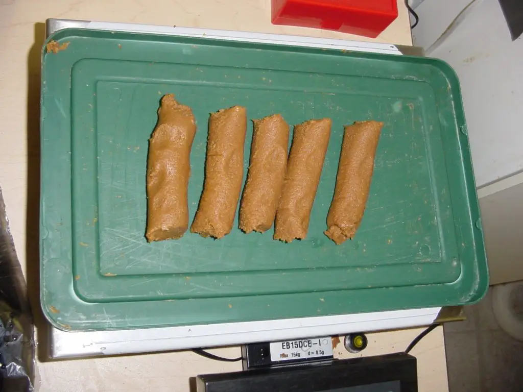 Five brown sausages on a green tray.