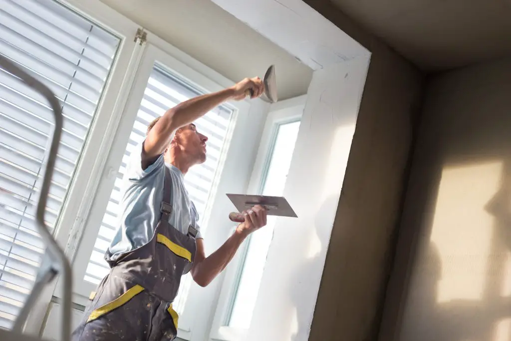 Worker plastering indoor window corner