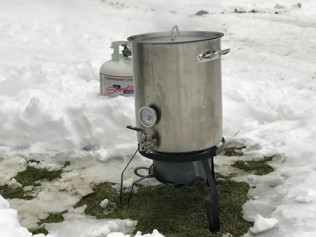 Outdoor propane kettle boiling in snowy landscape.