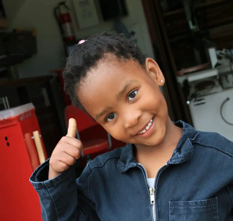 Child smiling with thumbs up.