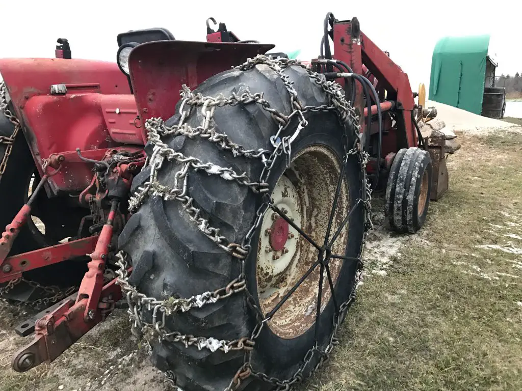 Tractor with chains on tires in winter field.