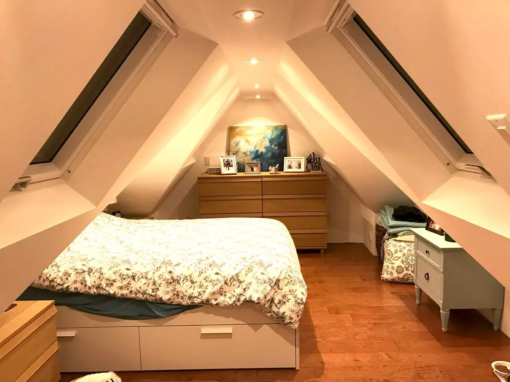 Cozy attic bedroom with skylights and wooden furniture.