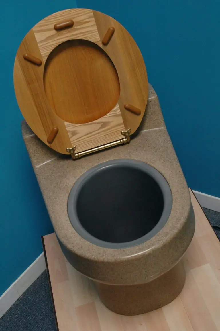 Composting toilet with open wooden lid.