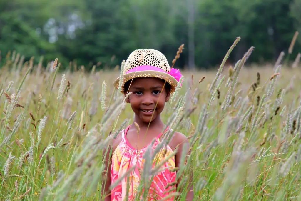 Smiling child in field wearing straw hat