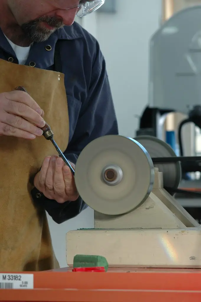 Man sharpening tool on a grinding wheel.