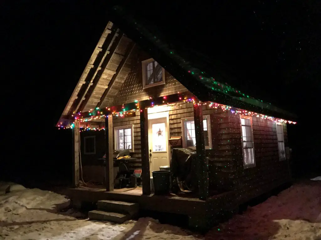 Rustic cabin with festive Christmas lights at night.