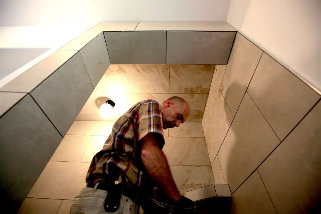 Man installing tiles in a shower