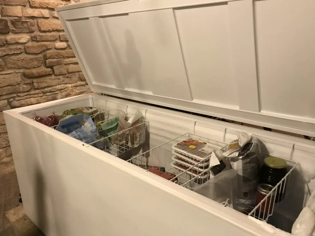 Open chest freezer with organized frozen food items.
