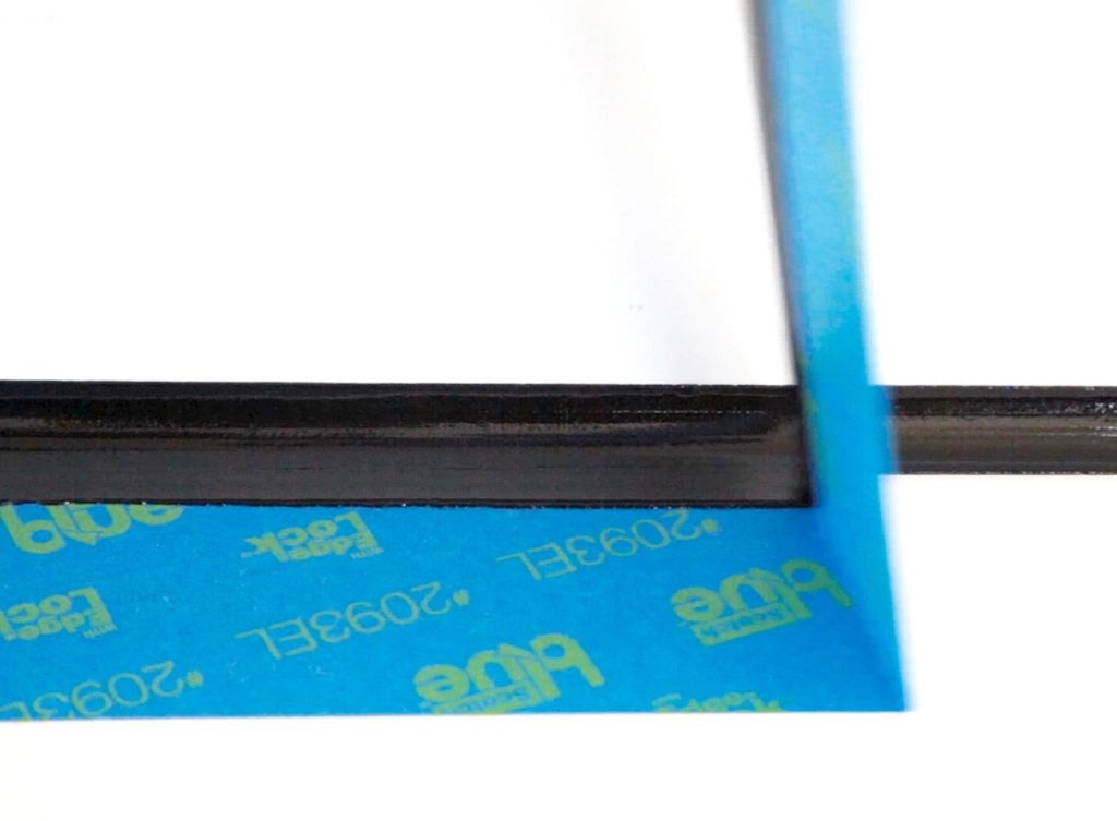 Black 3D printer part on blue tape background.