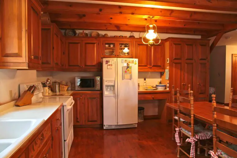 Cozy wooden kitchen with fridge and dining table.