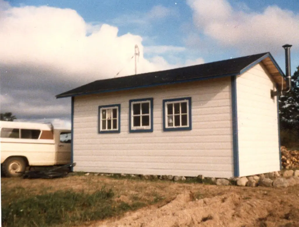 White wooden cabin with blue trim and windows.