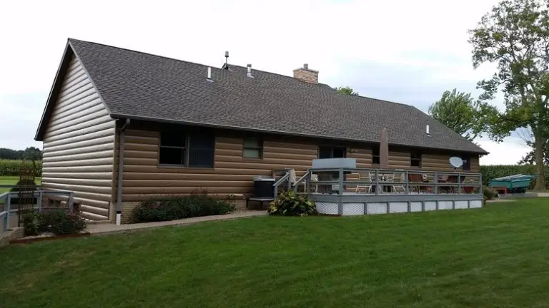 Modern log cabin with spacious deck and lawn.