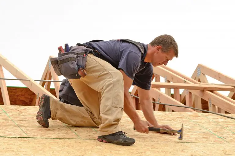 Construction worker hammering on roof framing.