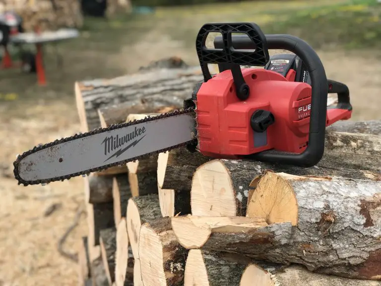 Red chainsaw on stacked logs outdoors